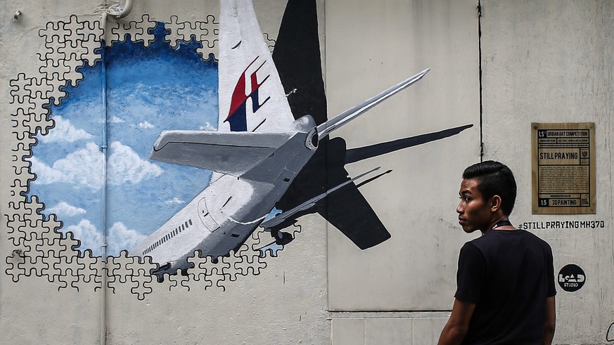 epa04865676 (FILE) A man stands in front of a Malaysia Airlines flight MH370 mural painting at Shah Alam, outside Kuala Lumpur, Malaysia, 06 March 2015. The Australian government minister in charge of ...