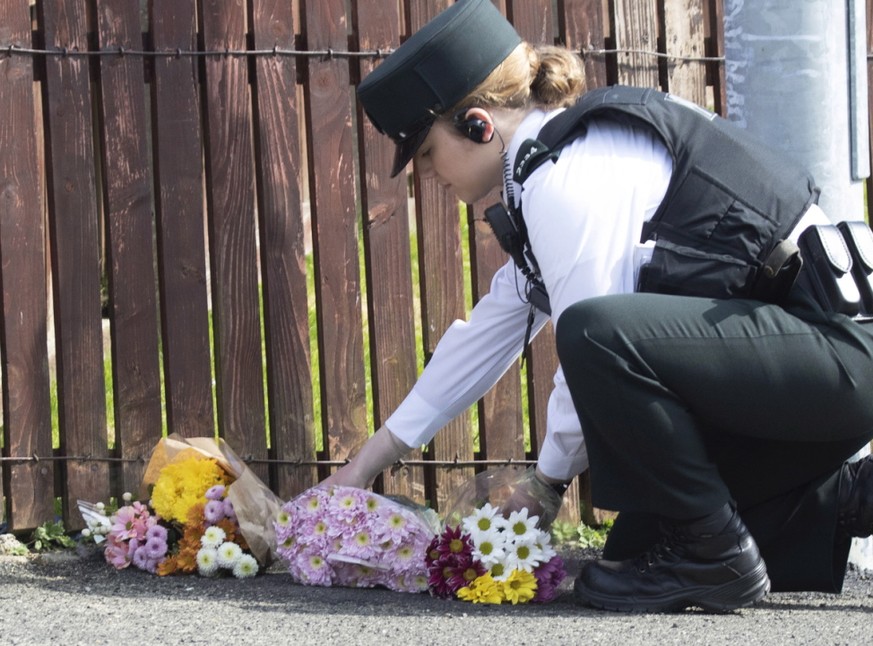 Eine Polizistin legt am Ort Blumen nieder, an dem in Derry eine 29-jährige Journalistin getötet wurde. Die Polizei meldete am Samstag die Festnahme von zwei Verdächtigen.