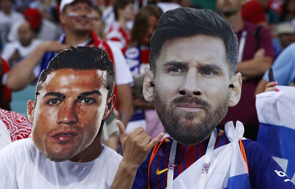 Fans wear masks with the face of the Portuguese national soccer star Cristiano Ronaldo and Argentina national soccer star Lionel Messi prior to the start of the quarterfinal match between Russia and C ...