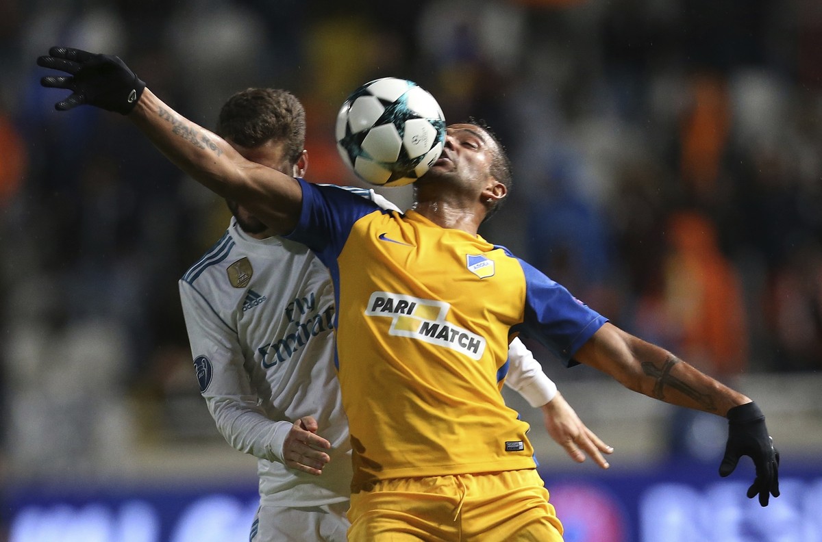 APOEL's Lorenzo Ebecilio, right, and Real Madrid's Nacho challenge for the ball during the Champions League Group H soccer match between APOEL Nicosia and Real Madrid at GSP stadium, in Nico ...
