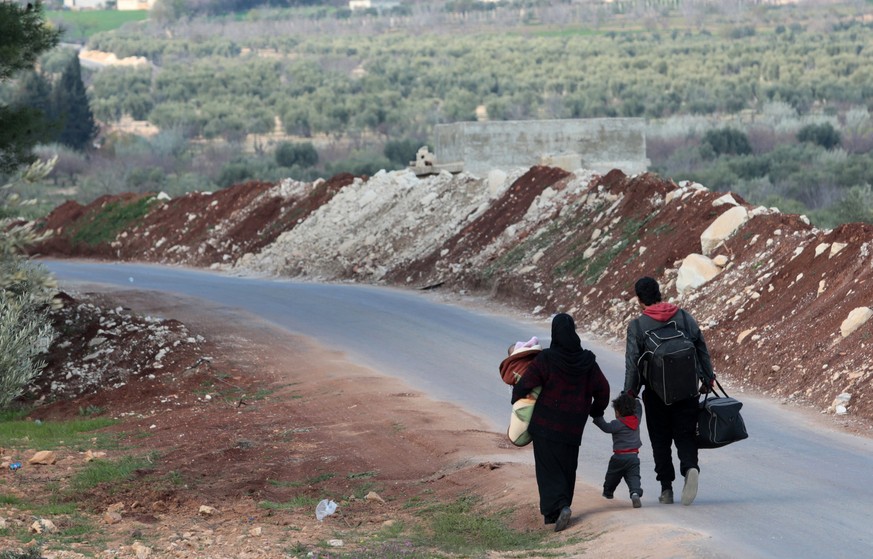 epa06600968 A Syrian family fleeing from fighting near Afrin walk to a secure area at Befalon Hills, as Turkey-backed Free Syrian Army surrounded of Afrin city with Turkish army in Syria, 13 March 201 ...