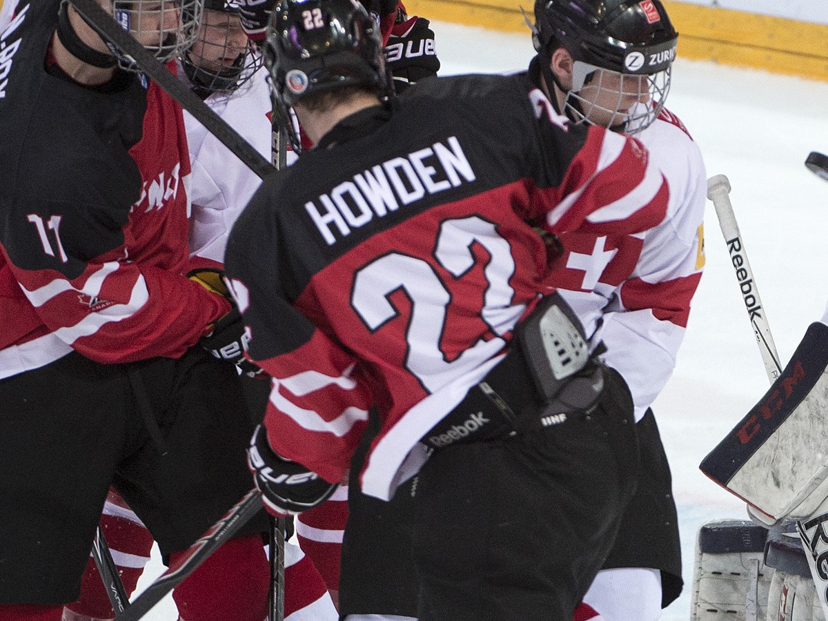 Switzerland's goalkeeper Joren van Pottelberghe, right, and Canada's Nicolas Roy, left, and Brett Howden, center, play for the puck during a the ice hockey U18 World Championships bronce med ...