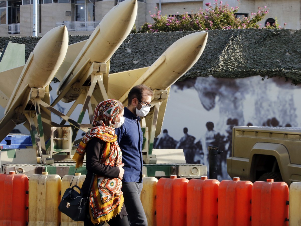 epa09487894 An Iranian couple walk next to short-range missiles in a street exhibition by Iran's army and paramilitary Revolutionary Guard celebrating 'Defence Week' marking the 41th an ...