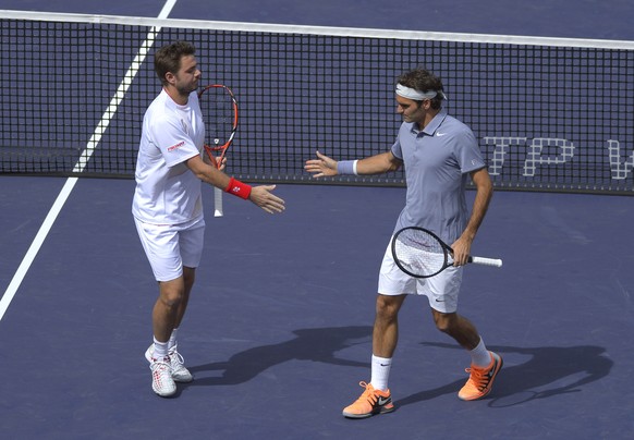 Roger Federer, of Switzerland, right, greets doubles partner Stanislas Wawrinka, of Switzerland, after scoring a point during a match at the BNP Paribas Open tennis tournament against Rohan Bopanna, of India, and Aisam-Ul-Haq Qureshi, of Pakistan,  Friday, March 7, 2014 in Indian Wells, Calif. (AP Photo/Mark J. Terrill)