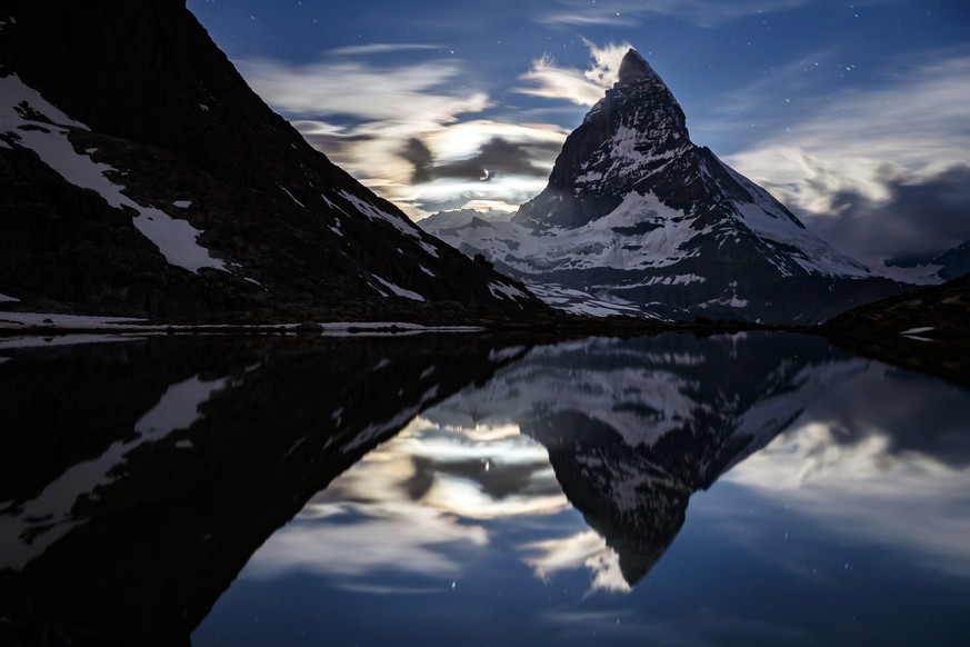 The moonset on the iconic Matterhorn mountain, peaking at 4478m, is pictured from the Riffelsee Lake in the Riffelberg area above the alpine village of Zermatt, Switzerland, Friday, June 22, 2018. (KE ...