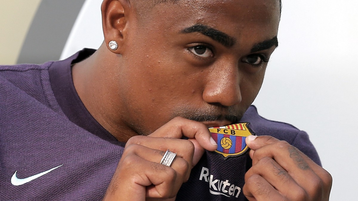 Brazilian soccer player Malcom Filipe Silva de Oliveira kisses the emblem on his shirt upon his arrival at the club's office at the Camp Nou stadium in Barcelona, Tuesday, July 24, 2018. Malcom h ...
