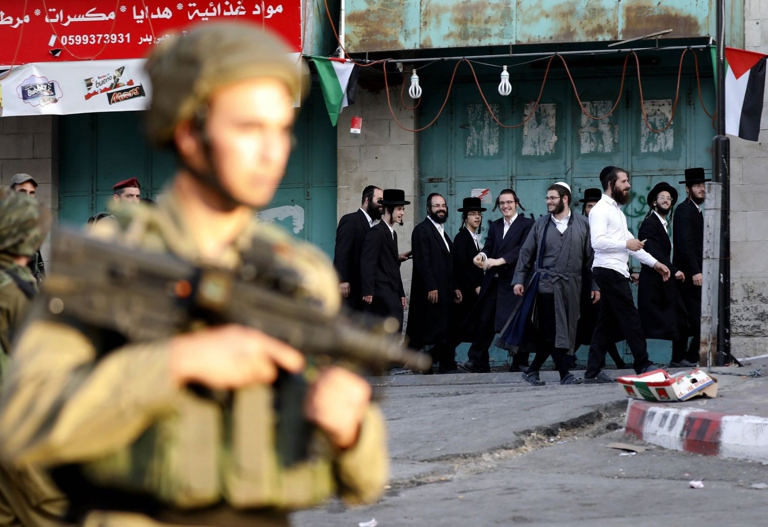 epa06120144 Israeli soldier stand guard while Ultra-Orthodox Jewish men under the protection of the soldiers visit a sacred Jewish site in the occupied West Bank city of Hebron, West Bank, 01 August 2 ...