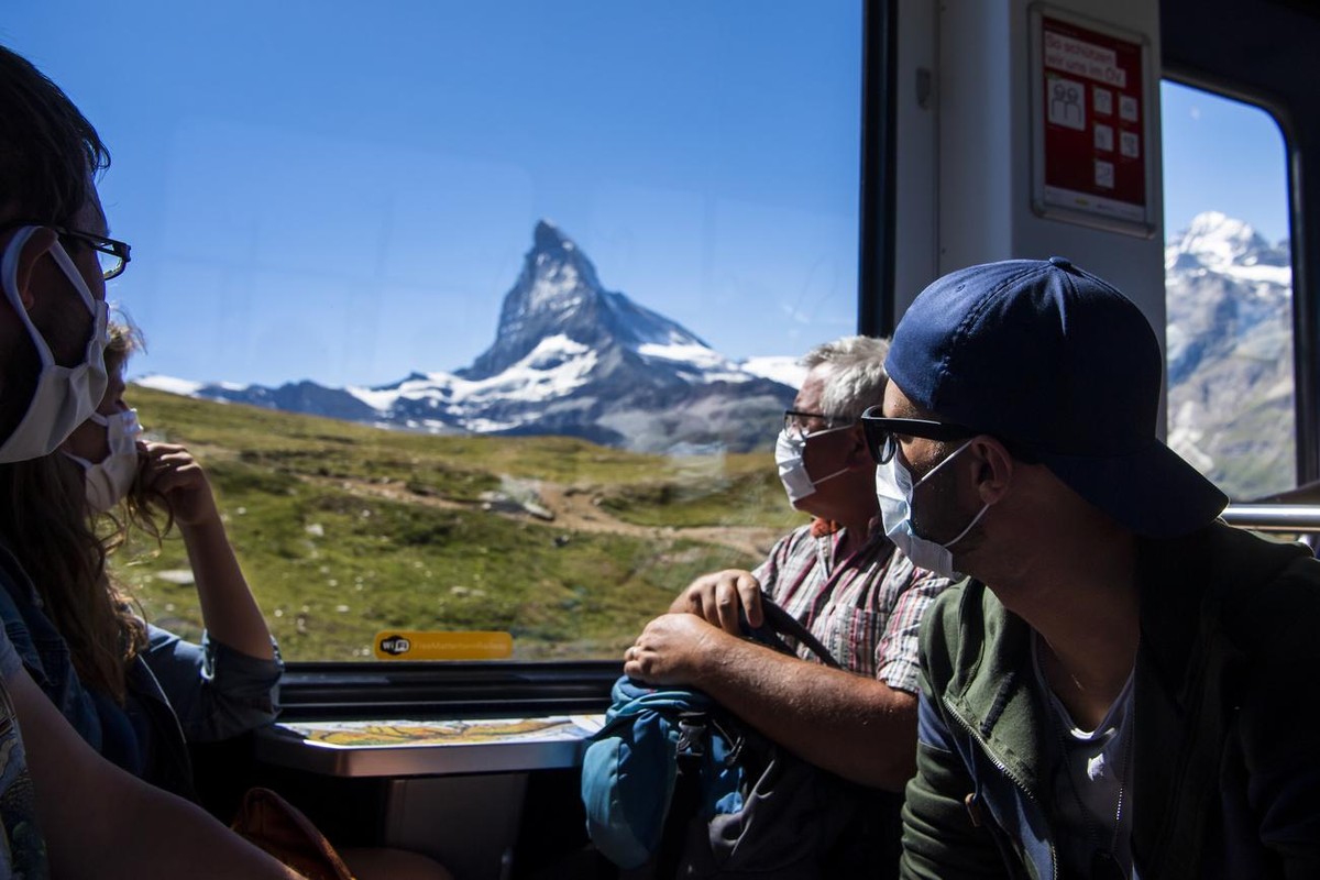 Des touristes portant un masque de protection descendent du Gornergrat au village de Zermatt dans le train du chemin de fer du Gornergrat devant le Cervin pendant la crise du Coronavirus (Covid-19) a  ...