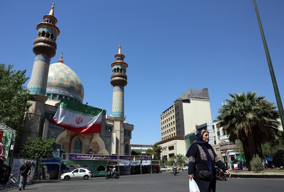 epa12947410 A woman walks next to a mosque in Tehran, Iran, 11 May 2026. US President Donald Trump says Irans counter-proposal to end the ongoing conflict is not acceptable. EPA/ABEDIN TAHERKENAREH