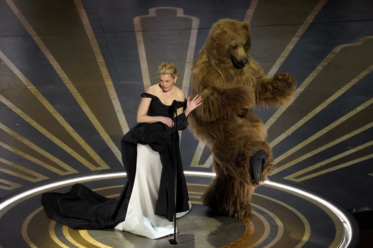 Elizabeth Banks, left, and an actor dressed in a costume from her movie "Cocaine Bear" present the award for best visual effects at the Oscars on Sunday, March 12, 2023, at the Dolby Theatre ...
