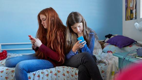 [Symbolic Image, Staged Picture, ] Sisters sitting on a bed, use their smart phones in their bedsitter, photographed in Lucerne, Switzerland, on December 13, 2015. (KEYSTONE/Christof Schuerpf)

[Geste ...