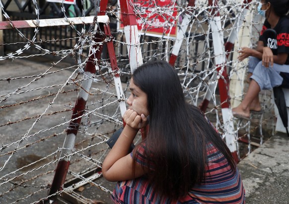 epa09530245 A woman sits near the barricade as she waits for the released of her family member outside the Insein prison in Yangon, Myanmar, 18 October 2021. Myanmar&#039;s junta chief Min Aung Haling ...