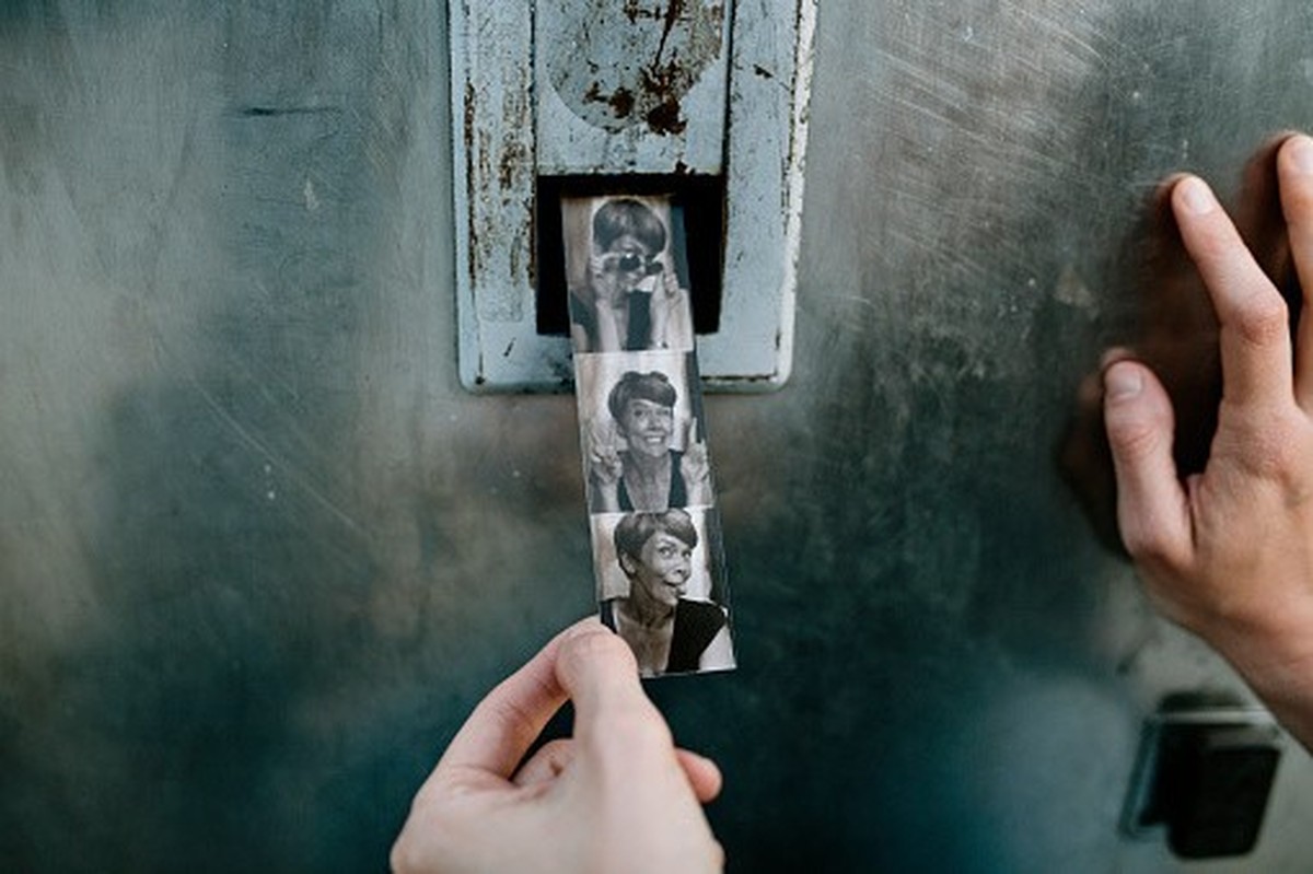 Woman collects her black and white photo strip from a public photobooth.