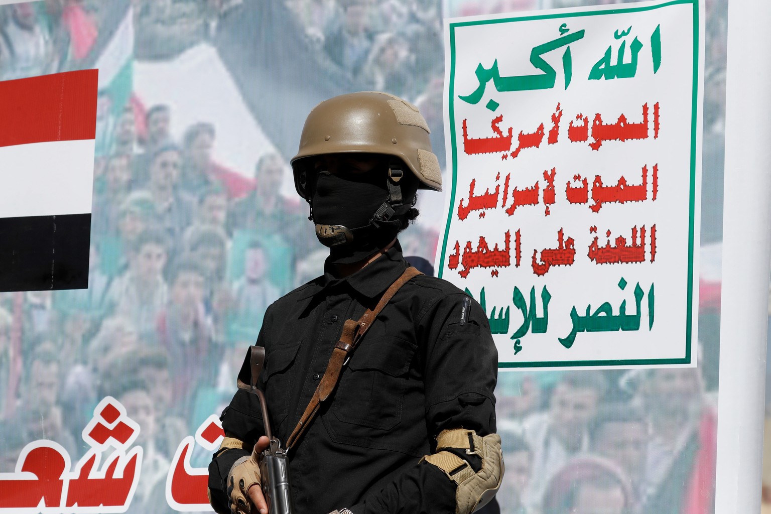 epa11070000 A Houthi trooper stands guard in front of a banner reading in Arabic &#039;Allah is the greatest of all, death to America, death to Israel, a curse on the Jews, victory to Islam&#039; duri ...