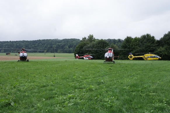 27.07.2025, Baden-Württemberg, Riedlingen: Vier Rettungshubschrauber stehen auf einem Feld nahe des Bahnunglücks. Ein Personenzug ist im Kreis Biberach zwischen den Ortsteilen Zweifaltendorf und Zell  ...