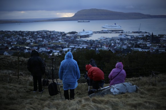 People wait for the start of a total solar eclipse on a hill beside a hotel overlooking the sea and Torshavn, the capital city of the Faeroe Islands, Friday, March 20, 2015. For months, even years, ac ...