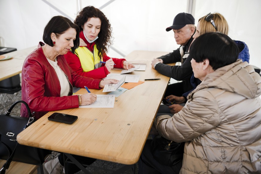 Christine Schraner Burgener, Staatssekretaerin f�r Migration, links, fuellt mit Fluechtlingen aus der Ukraine die Registrierungsformulare beim Bundesasylzentrum Zuerich aus, am Sonntag, 13. Maerz 2022 ...