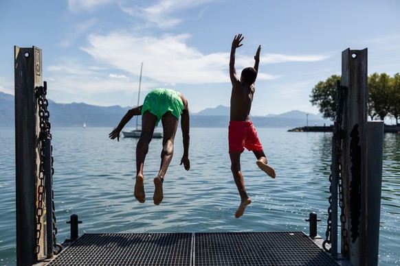 A father and his son are diving from a deck during a very warm day near Ouchy harbor, in Lausanne, Switzerland, Friday, August 18, 2023. (KEYSTONE/Pierre Albouy)
