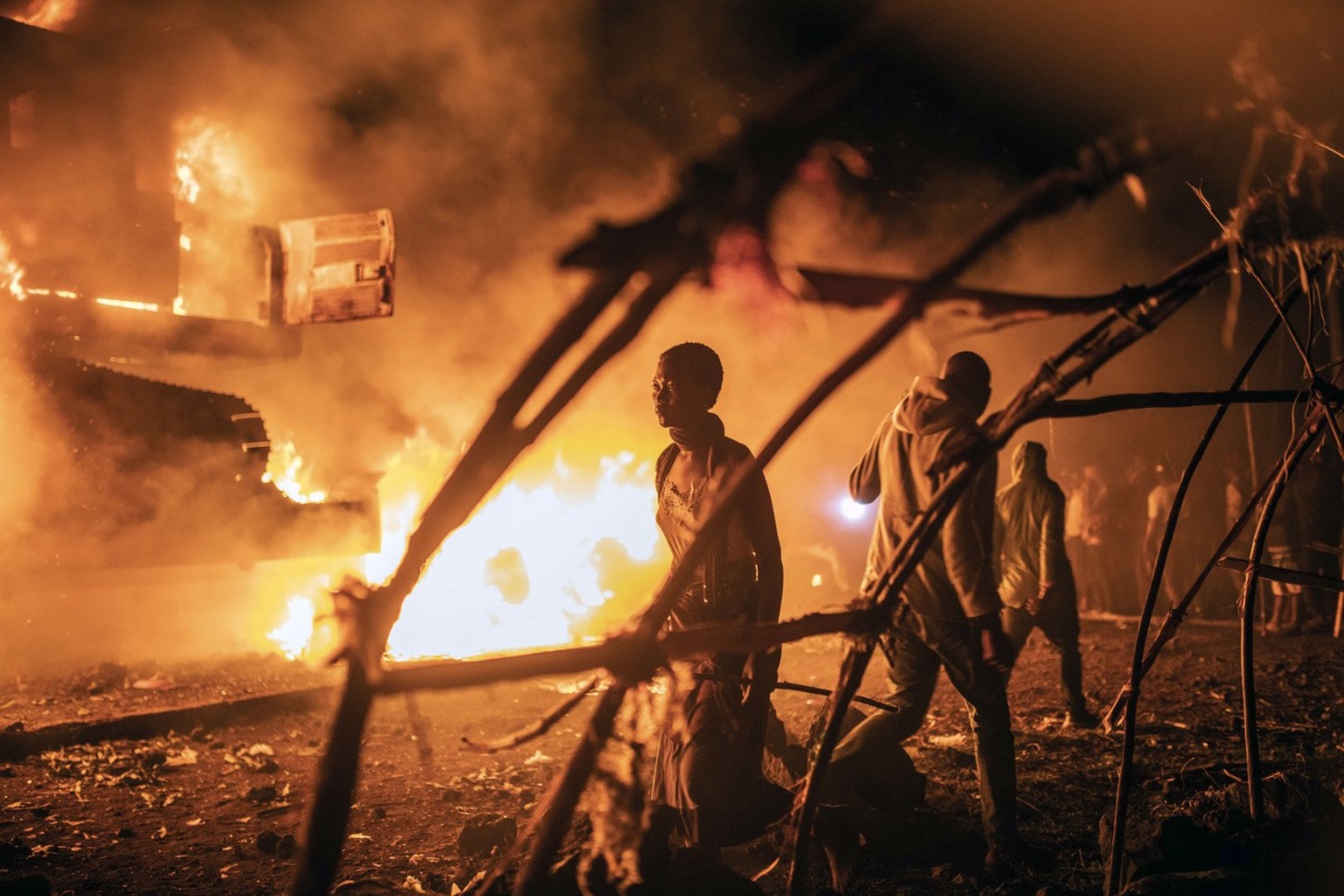People walk by U.N. vehicles which were set on fire, in Goma, Democratic Republic of Congo, Tuesday Nov. 1, 2022. Angry crowds in eastern Congo have set fire to U.N. vehicles as frustrations mount ove ...