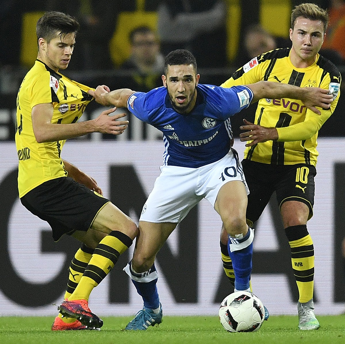 Dortmund's Julian Weigl, Schalke's Nabil Bentaleb and Dortmund's Mario Goetze, from left, challenge for the ball during the German Bundesliga soccer match between Borussia Dortmund and  ...