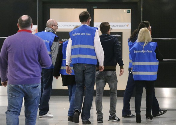 Airport staff walk to a non-public area where people waiting for the Germanwings flight from Barcelona have been brought at the airport in Duesseldorf, Germany, Tuesday, March 24, 2015, after a German ...