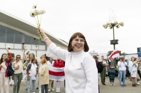 Belarusian opposition activist Olga Kovalkova waves with flowers during a protest in Minsk, Belarus, Saturday, Aug. 22, 2020. Demonstrators are taking to the streets of the Belarusian capital and othe ...