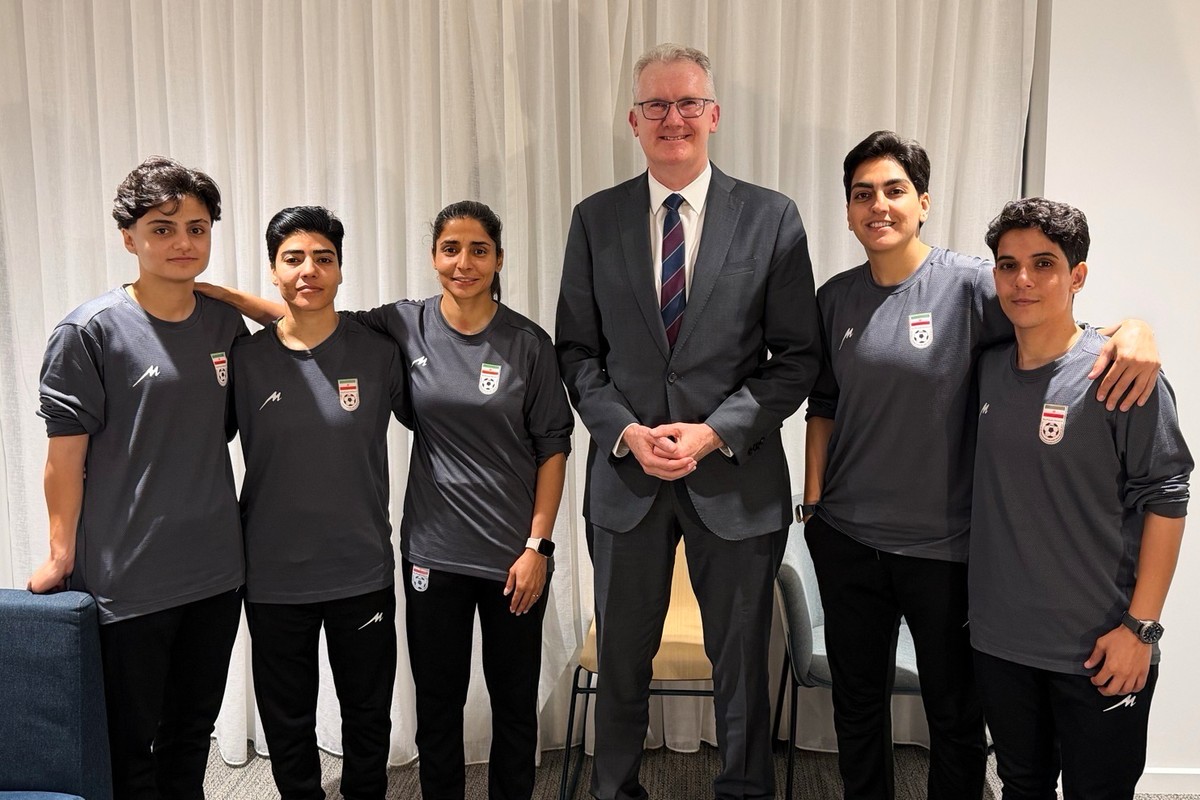 In this photo supplied by Australia's Minister for Home Affairs Tony Burke's office, the Minister Tony Burke, center, poses in an undisclosed location with five Iranian women soccer players  ...