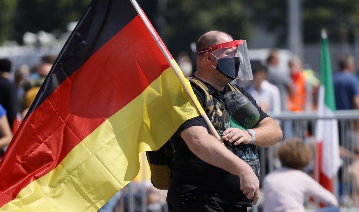 epa08426051 A man hold a German flag during a demonstration of the initiative 'Lateral thinking' in Stuttgart, Germany, 16 May 2020. The demonstration is directed against the Coronavirus res ...
