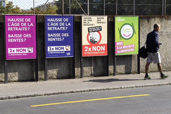 Une personne passe devant des affiches sur les differents themes des votations federales, donc l&#039;arrete federal sur le financement additionnel de L&#039;assurance-vieillesse et survivants (AVS- A ...