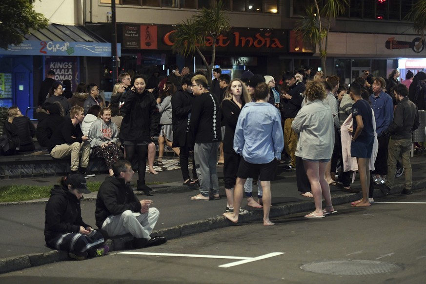 People evacuated from buildings along Dixon Street stand and sit on the street and the sidewalk in Wellington after a 6.6 earthquake based around Cheviot in the South island shock the capital, New Zea ...