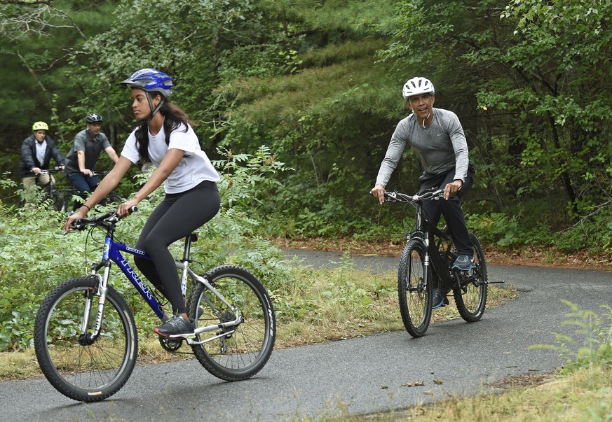 FILE - In this Aug. 22, 2015 file photo, President Barack Obama, right, follows his daughter Malia as they rides their bikes in West Tisbury, Mass., on Martha&#039;s Vineyard. Obama and his family are ...