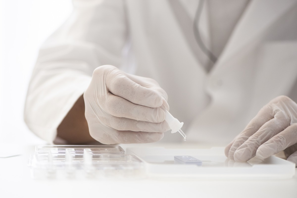 Pflegefachmann Markus Stratmann tropft mit einer Pipette die Testloesung auf das Tesgeraet mit dem eingelegten Papier-Teststreifen, mit dem Covid-19 Antigene nachgewiesen werden koennen in der Praxis  ...