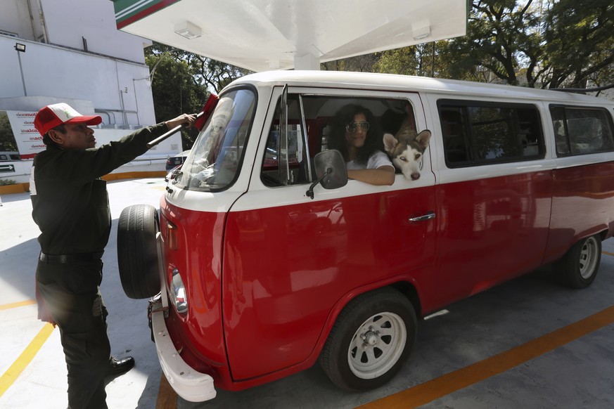 In this Wednesday, Dec. 27, 2017 photo, Jair Benavides has his Volkswagen van fueled at a gas station as he takes his dogs on a day trip, in Mexico City. Jair and his wife Mariam Gutierrez de Velasco  ...