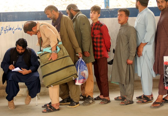epaselect epa12851573 Afghan nationals prepare to board a bus after they cross into Afghanistan, following their repatriation from neighboring Pakistan, after the partial reopening of the Torkham bord ...