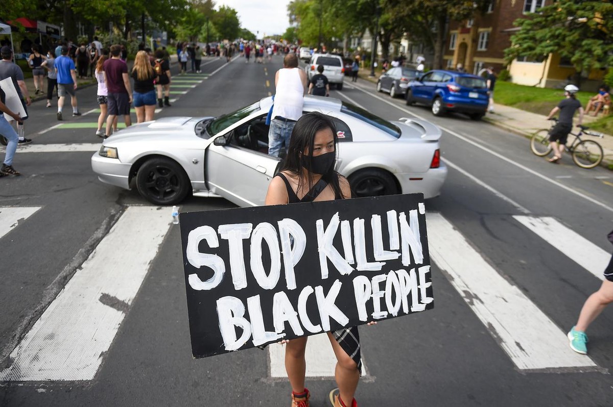 epa08446259 Amy Gee of Minneapolis holds a sign near the scene of the arrest of George Floyd, who later died in police custody, in Minneapolis, Minnesota, USA, 26 May 2020. A video posted online one 2 ...