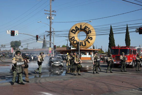 epa12163174 Law enforcement stand in front of a burned car near a Home Depot after a raid was conducted by Immigration and Customs Enforcement (ICE) in Paramount, California, USA, 07 June 2025. This c ...