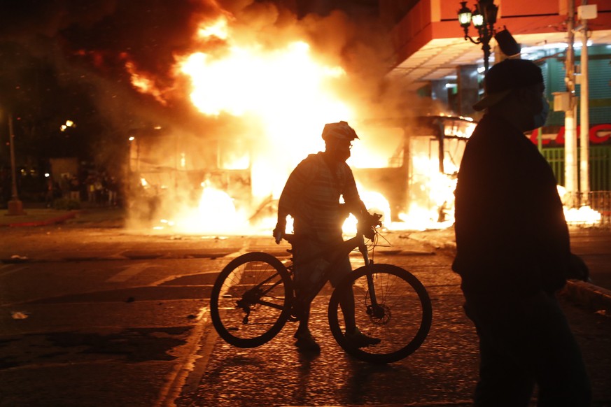 epa08850120 Protesters gather as a bus burns in front of the National Palace, in Guatemala City, Guatemala, 28 November 2020. A group of hooded demonstrator burned a bus on the corner of the National  ...