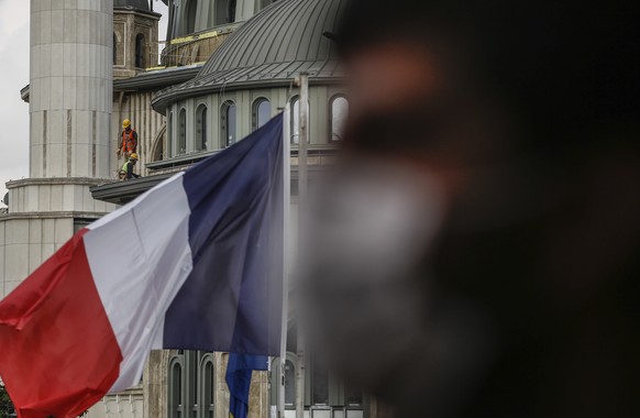 Builders work on a mosque still under construction in Istanbul&#039;s Taksim Square as the French flag flies on the premises of France&#039;s consulate in Istanbul, Wednesday, Oct. 28, 2020. Turkish o ...