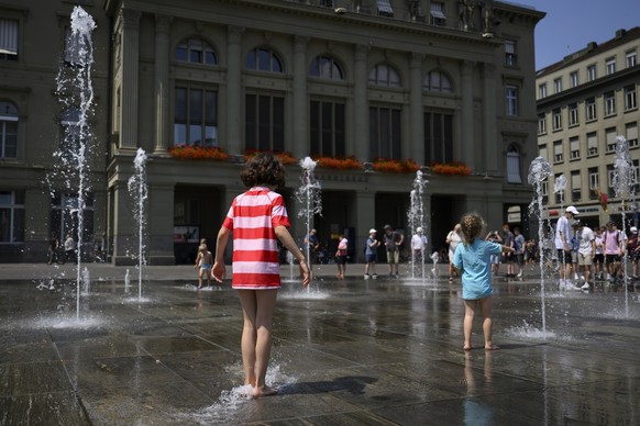 Menschen geniessen das warme Wetter beim Wasserspiel auf dem Bundesplatz in Bern, Schweiz, am Mittwoch, 20. Juli 2022. (KEYSTONE/Anthony Anex). Die aktuelle Hitzewelle hat ihren vorläufigen Höhepunkt  ...