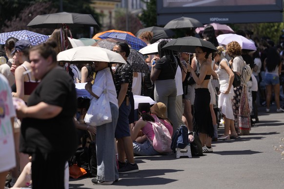 People wait in the heat the arrival of guests of the Prada's Spring/Summer 2027 men's collection presented in Milan, Italy, Sunday, June 21, 2026. (AP Photo/Luca Bruno)
Italy Fashion Prada S ...