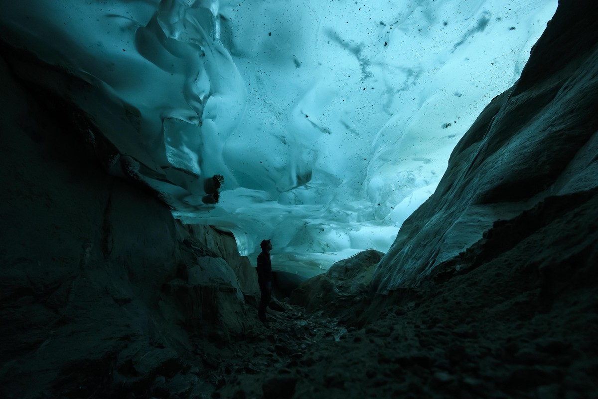 epa08416305 A man watches the ice in an ice cave in the Swiss Aletsch Glacier, in Valais, Switzerland, 25 September 2019 (reissued 12 May 2020). Turquoise, originally the French word for 'Turkish ...
