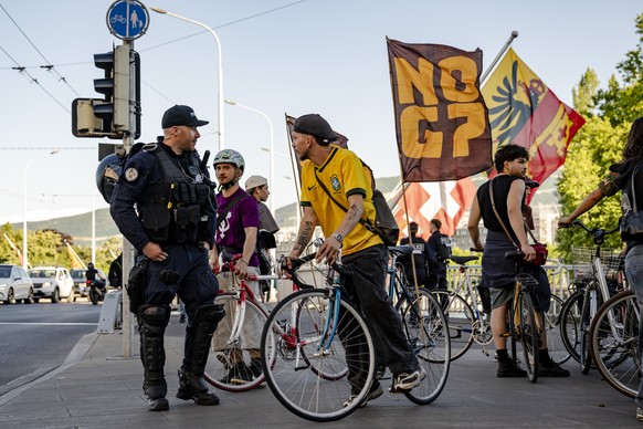 epaselect epa13033357 A Swiss police officer checks cyclists' identification during a bicycle rally 'Critical Mass No-G7' ahead of the upcoming G7 summit, in Geneva, Switzerland, 12 Jun ...
