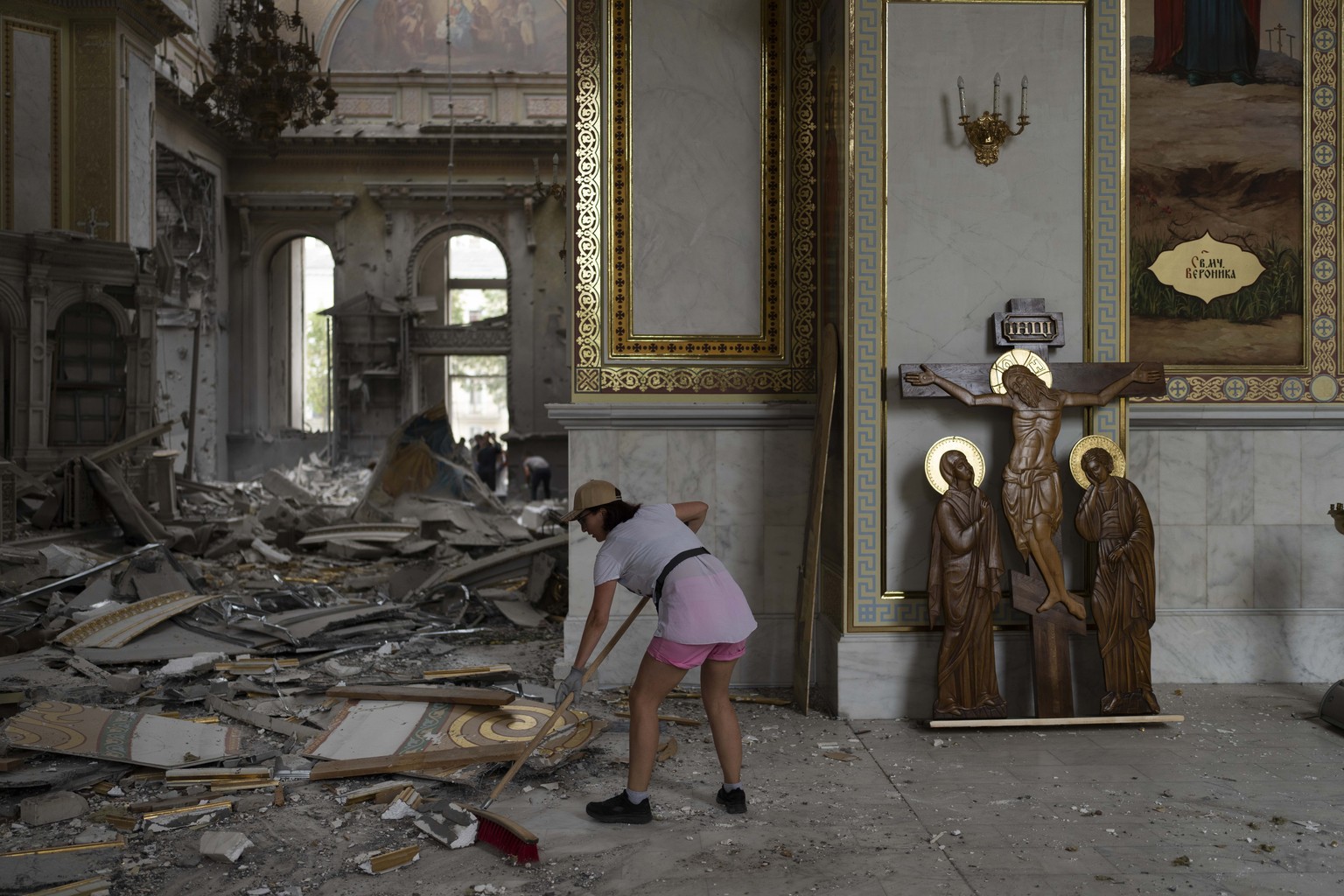 A woman helps clean up inside the Odesa Transfiguration Cathedral after it was heavily damaged in Russian missile attacks in Odesa, Ukraine, Sunday, July 23, 2023. (AP Photo/Jae C. Hong)