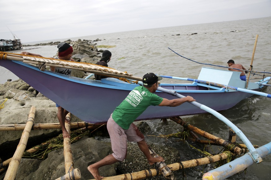 epa06392648 Filipino fishermen secure a boat at a coastal village in Cavite city, Cavite province, Philippines, 16 December 2017. The National Disaster Risk Reduction and Management Council (NDRRMC) r ...