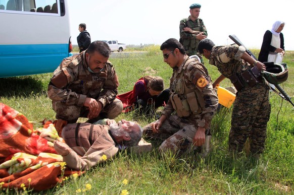 Kurdische Soldaten kümmern sich um einen älteren Mann