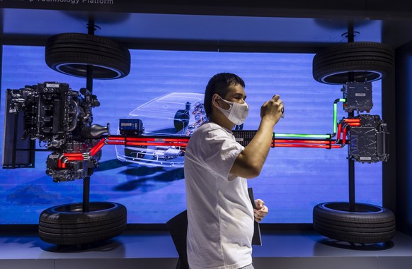 epa09148980 A visitor looks at the electric drivetrain on display at the BYD trade fair stand during the first day of the Auto Shanghai 2021 motor show in Shanghai, China, 21 April 2021. The 19th Inte ...