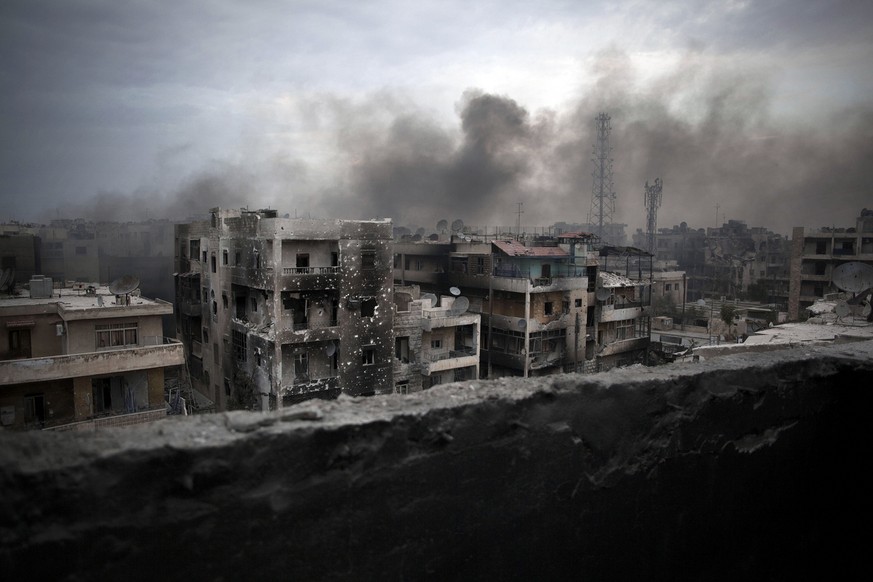 FILE - In this Oct. 2, 2012 file photo, smoke rises over Saif Al Dawla district, in Aleppo, Syria. The United States is outlining no change in its Syria policy as an August 1 target date for a politic ...