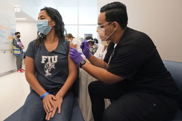 Jason Rodriguez, right, a University of Florida Pharmacy student, gives Camila Gutierrez, 21, a junior at Florida International University from Bolivia, the Pfizer COVID-19 vaccine at the Christine E. ...