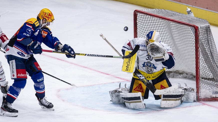 Zuerichs Top Scorer PostFinance Denis Hollenstein, links, kaempft um den Puck gegen Zugs Torhueter Leonardo Genoni, rechts, im Eishockeyspiel der National League zwischen den ZSC Lions und dem EV Zug  ...