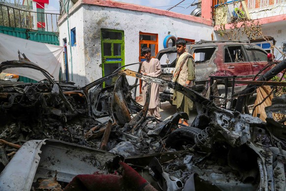 epa09476246 Family members of the victims of a US drone strike, stand beside the wreckage of the damaged vehicles, at their home, a day after US apologised for mistakenly attacking the civilians, in K ...